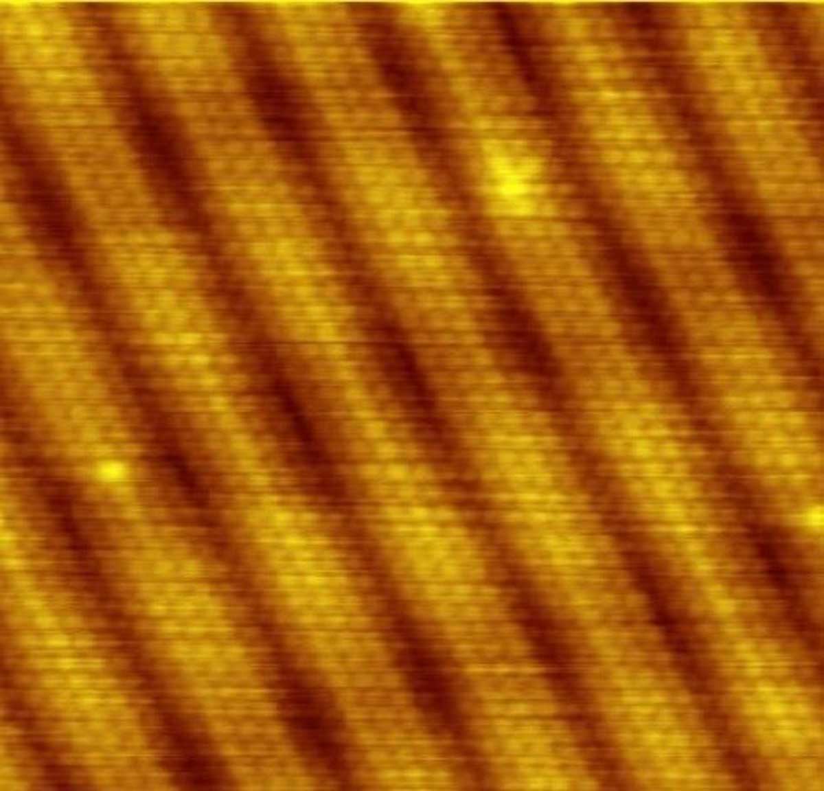金表面的 STM 图像。 单个原子及其排列是直接可见的。 暗带对应于表面的凹坑，没有原子。